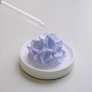 FLCSIed passive diffuser with porcelain peony on a wood base for subtle room fragrance.