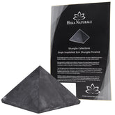 Heka Naturals shungite pyramid on desk purifies surroundings and elevates ambiance.