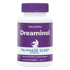 NaturesPlus DREAMINOL Tri-Phase Sleep Complex bottle on a nightstand for calmer bedtimes.