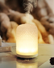 Onaboviva diffuser with glass base rests on a shelf delivering a subtle inviting aroma