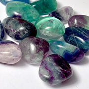 Pachamama Essentials Rainbow Fluorite tumbled stone close-up, highlighting vibrant banding for focus and balance.