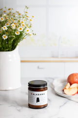 Rambling Caravan Alabama State Candle jar showcases warm wax tones for inviting spaces.