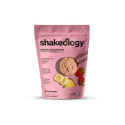 Shakeology tropical strawberry powder jar, gluten-free vegan protein blend for daily nutrition.