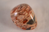 The Chrysalis Stone Brecciated Jasper tumbled stone showing orange-red bands for grounding.