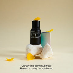 Bottle of Vitruvi Retreat with drops showing grapefruit and eucalyptus notes