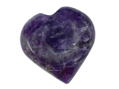 Amazing Gemstone amethyst heart palm stone glows softly beside crystal grids in a calm space.