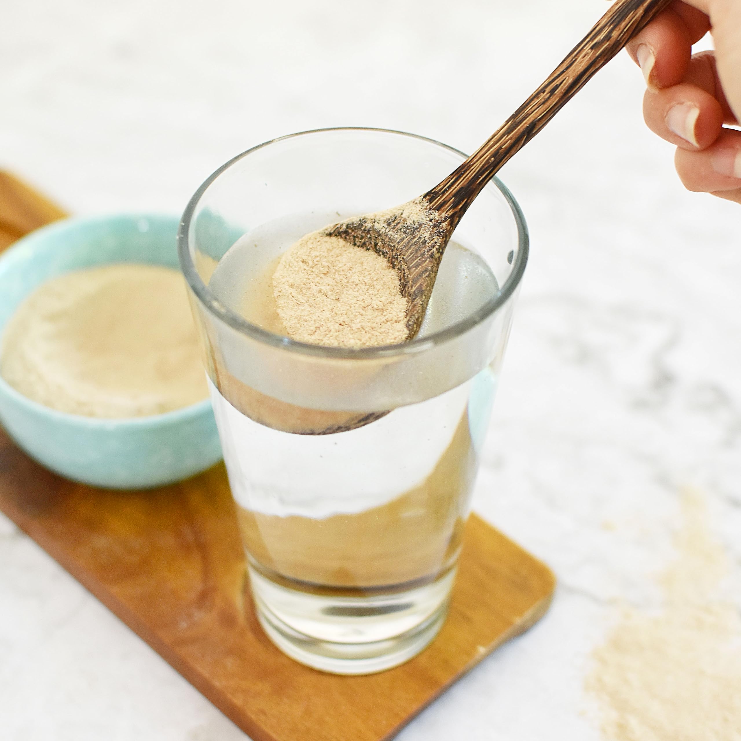 Psyllium powder being stirred into a glass, ready to mix.