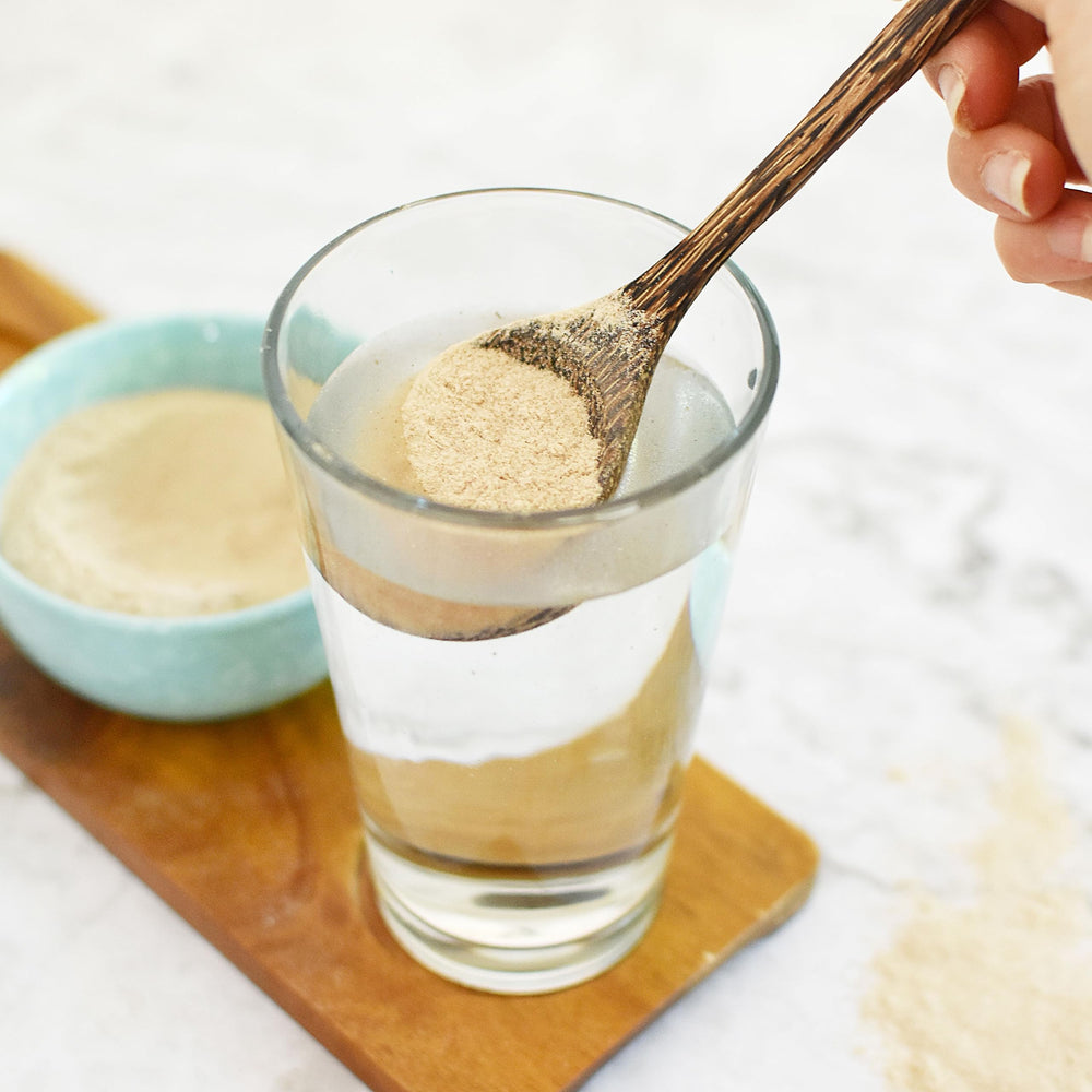 Psyllium powder being stirred into a glass, ready to mix.