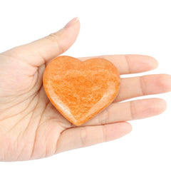 Artistone orange calcite heart in hand for calming touch and grounding