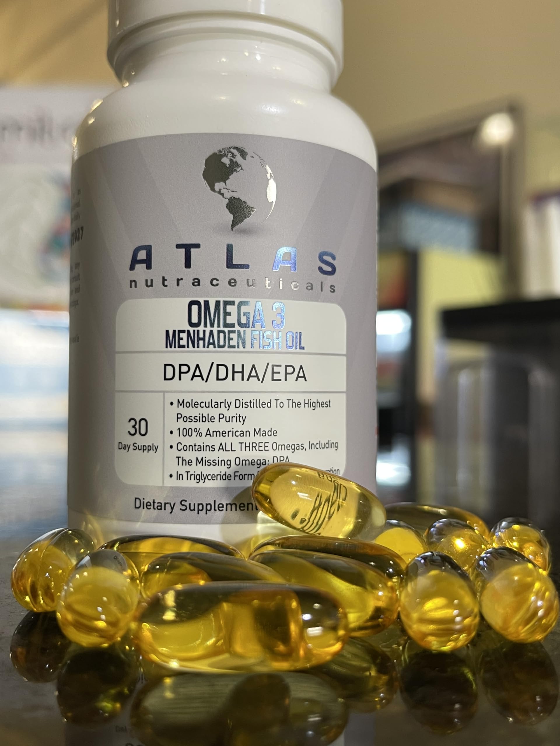 Atlas Nutraceuticals fish oil capsules resting beside a glass of water.
