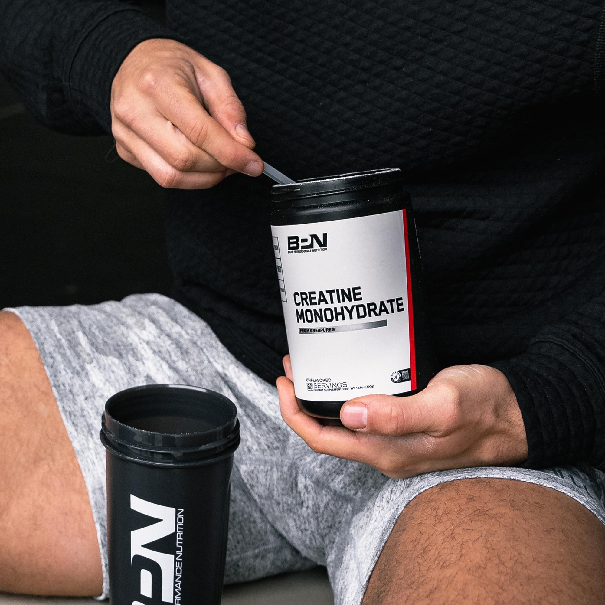 Stirring Bare Performance Nutrition creatine into a drink after workout.