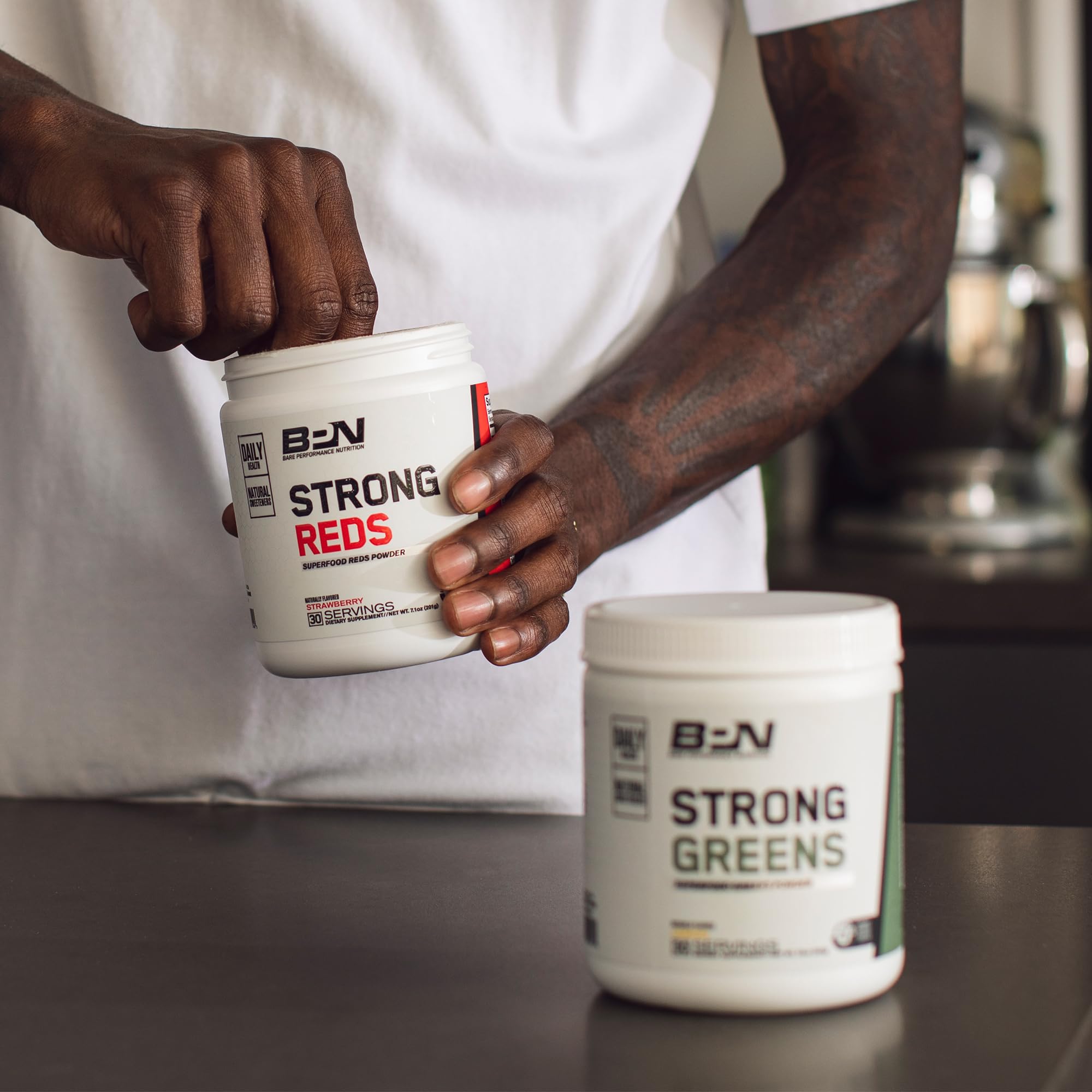 BARE PERFORMANCE NUTRITION Strong Greens Lemon glass with powder and citrus zest.