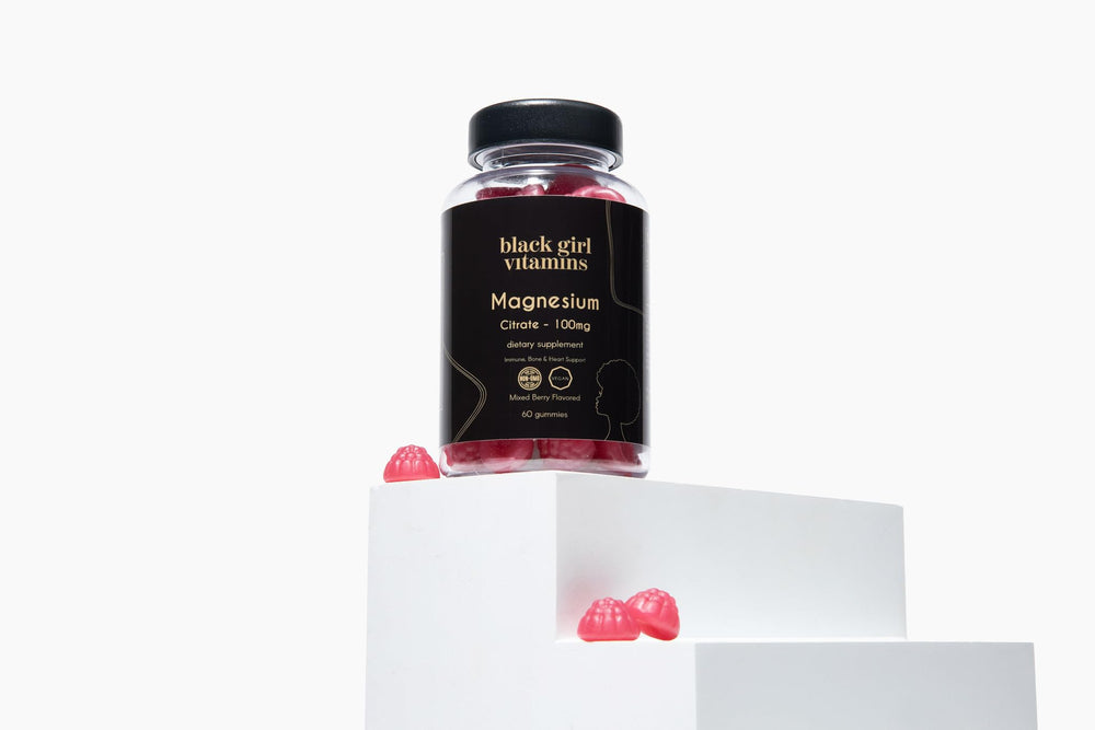 Black Girl Vitamins magnesium gummies on nightstand beside lamp for bedtime routine.