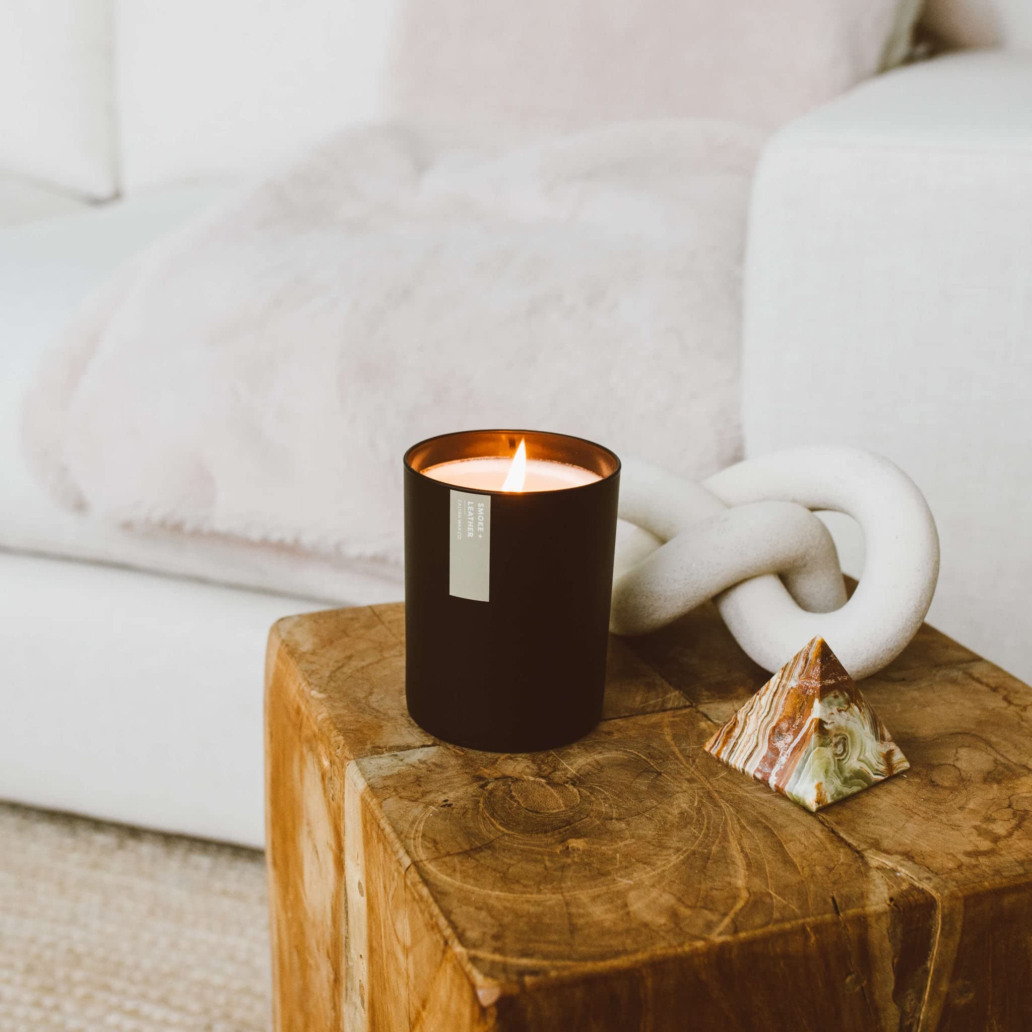 Calyan Wax Co. Smoke & Leather candle in a black tumbler on a coffee table.
