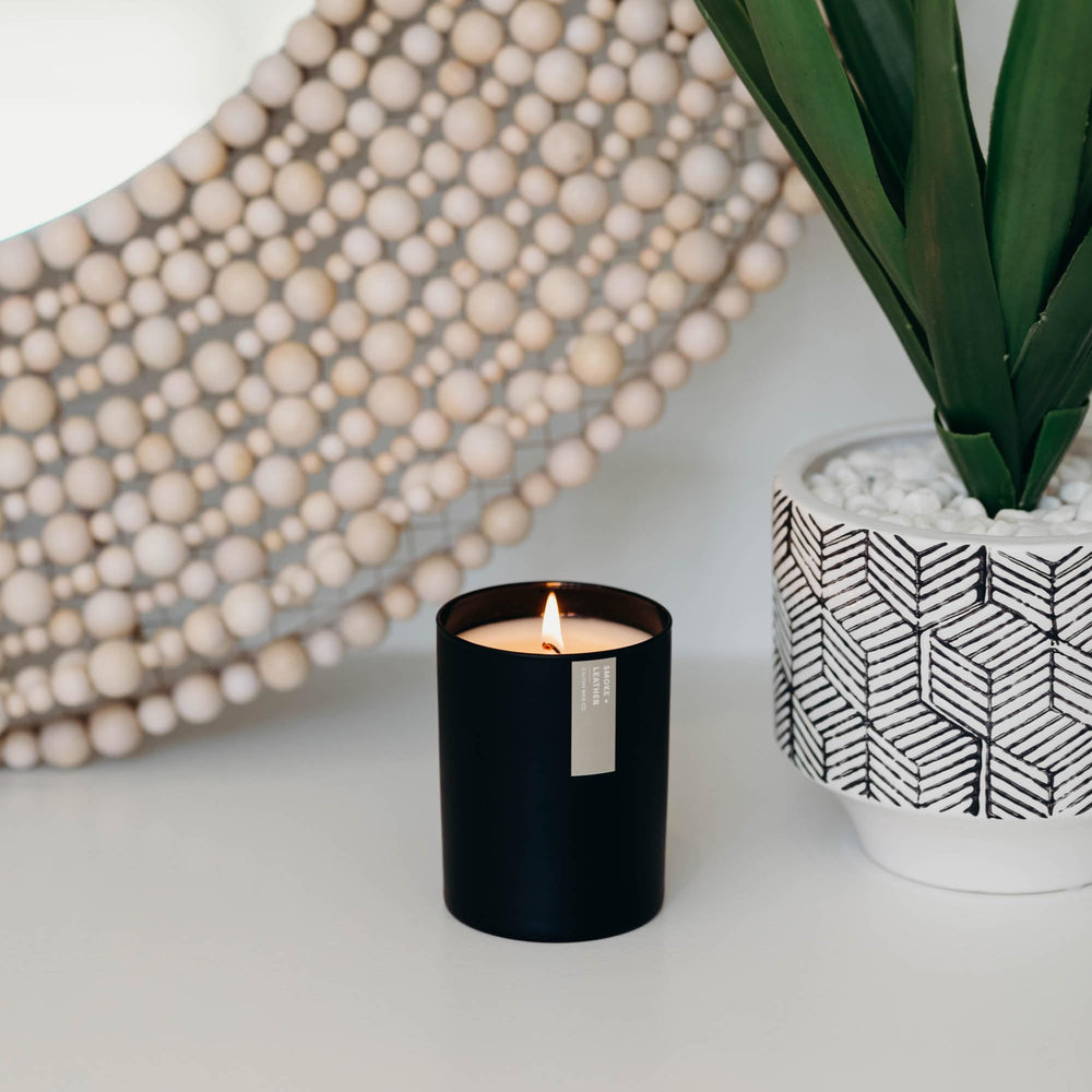 Calyan Wax Co. candle near pine and cedar decor suggests seasonal ambiance.
