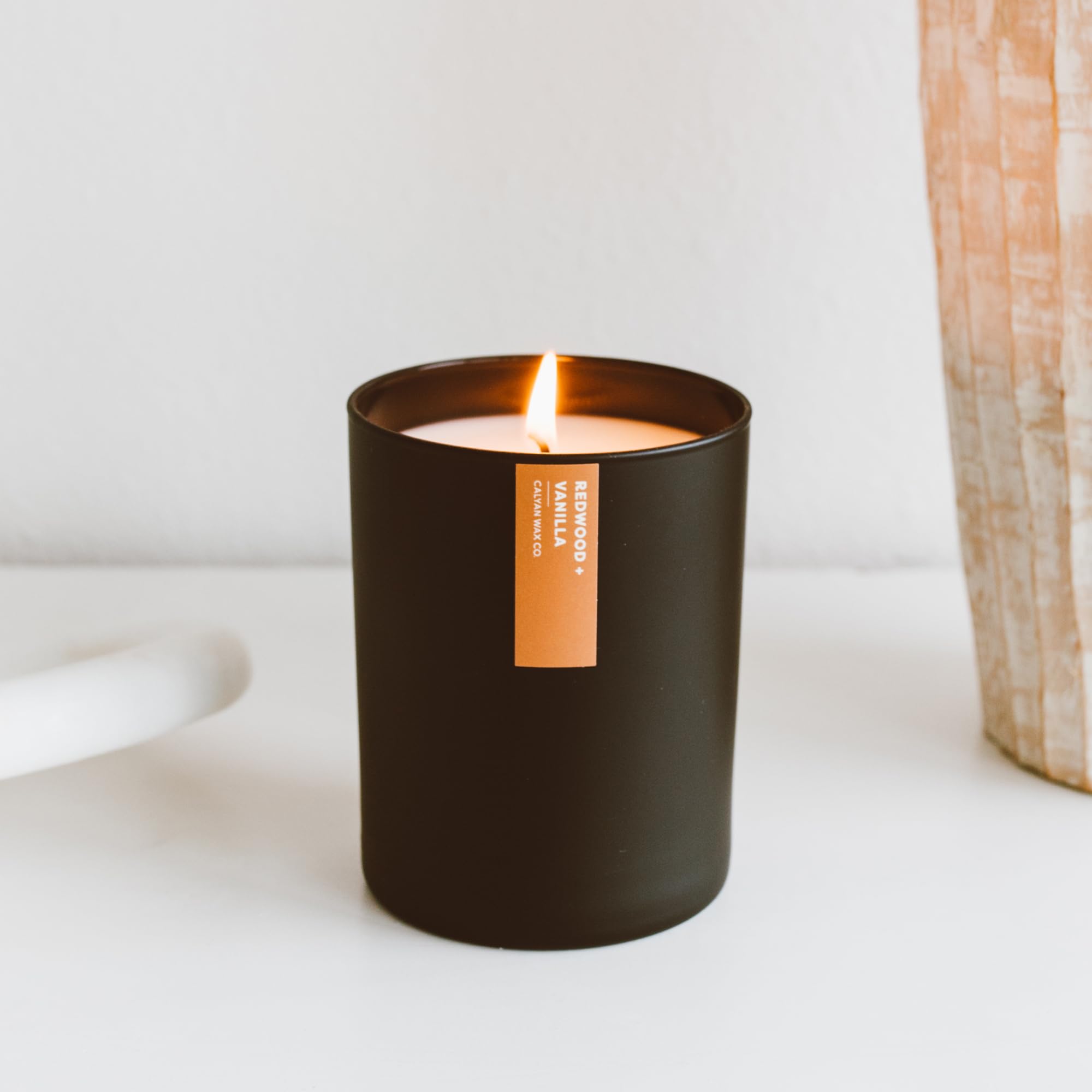 Calyan Wax Co. Redwood & Vanilla candle close-up shows warm amber and sandalwood depth.
