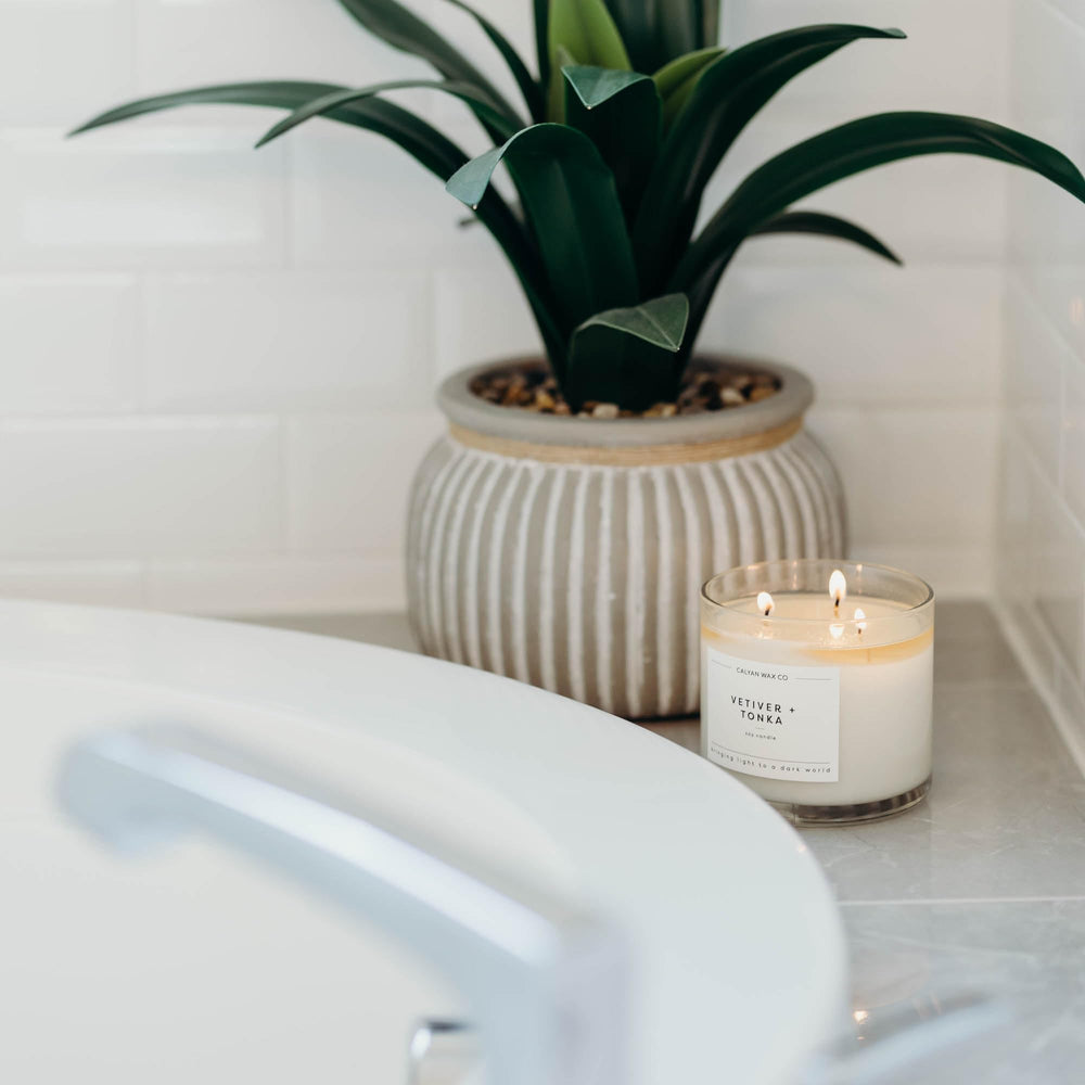 Calyan Wax Co Vetiver and Tonka 3 Wick candle lit, ambient glow fills the room.