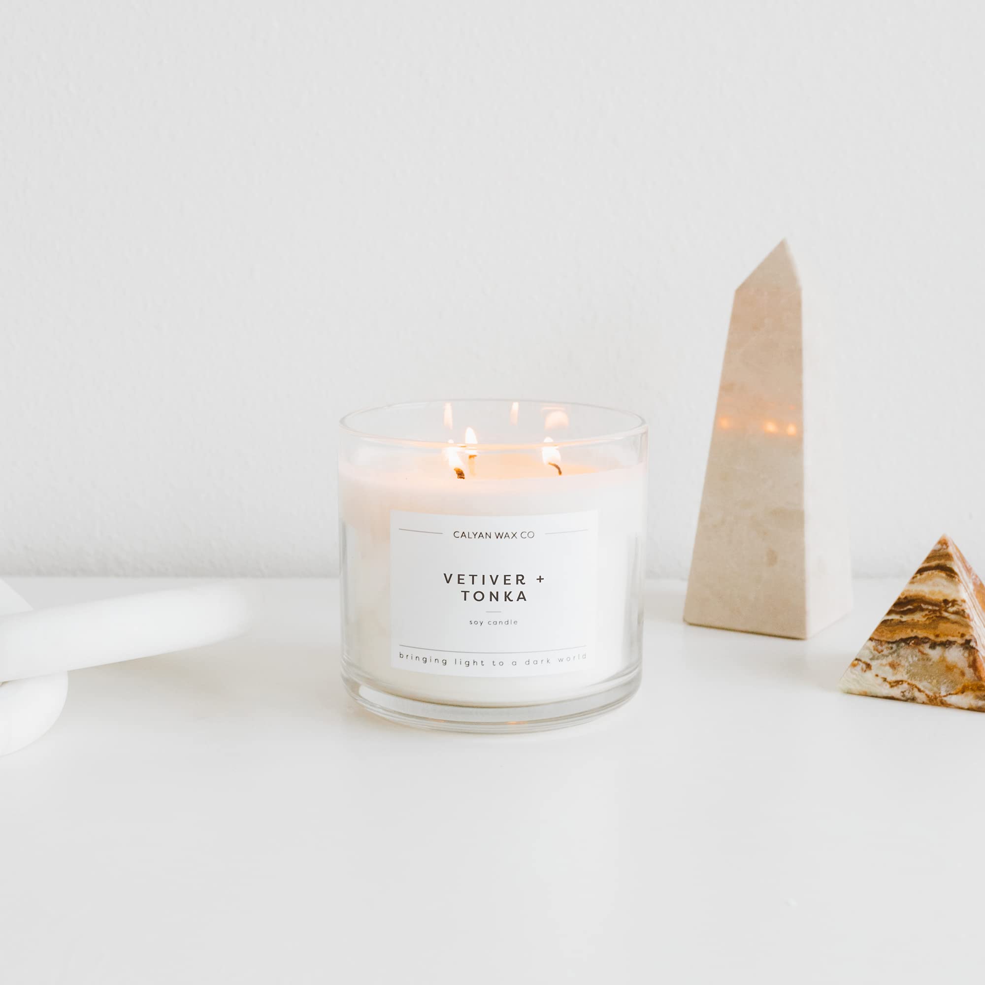 Calyan Wax Co Vetiver and Tonka 3 Wick candle on a coffee table, cozy ambience.