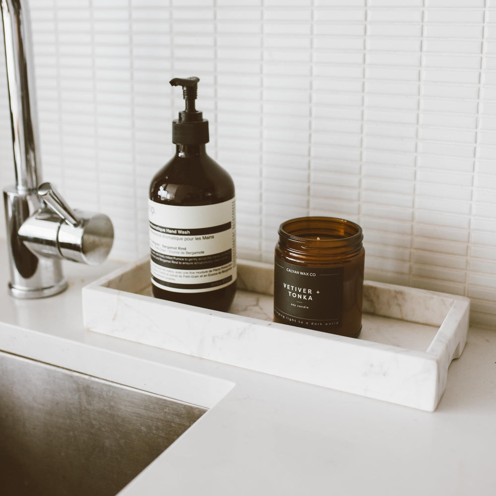 Calyan Wax Co Vetiver and Tonka candle in a cozy room ambiance with warm lighting.