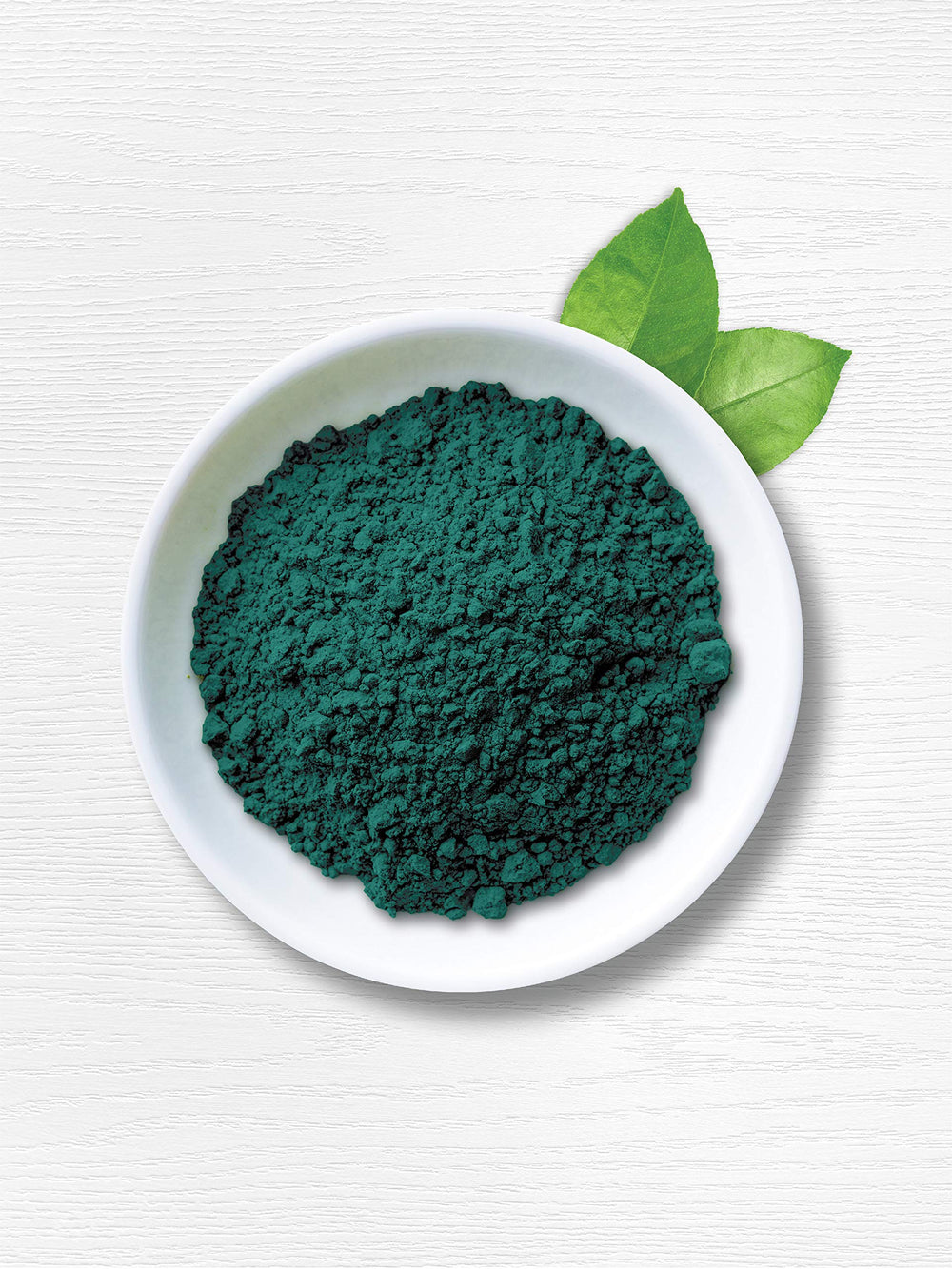 Carlyle spirulina powder being stirred into smoothie for a nutrient boost.
