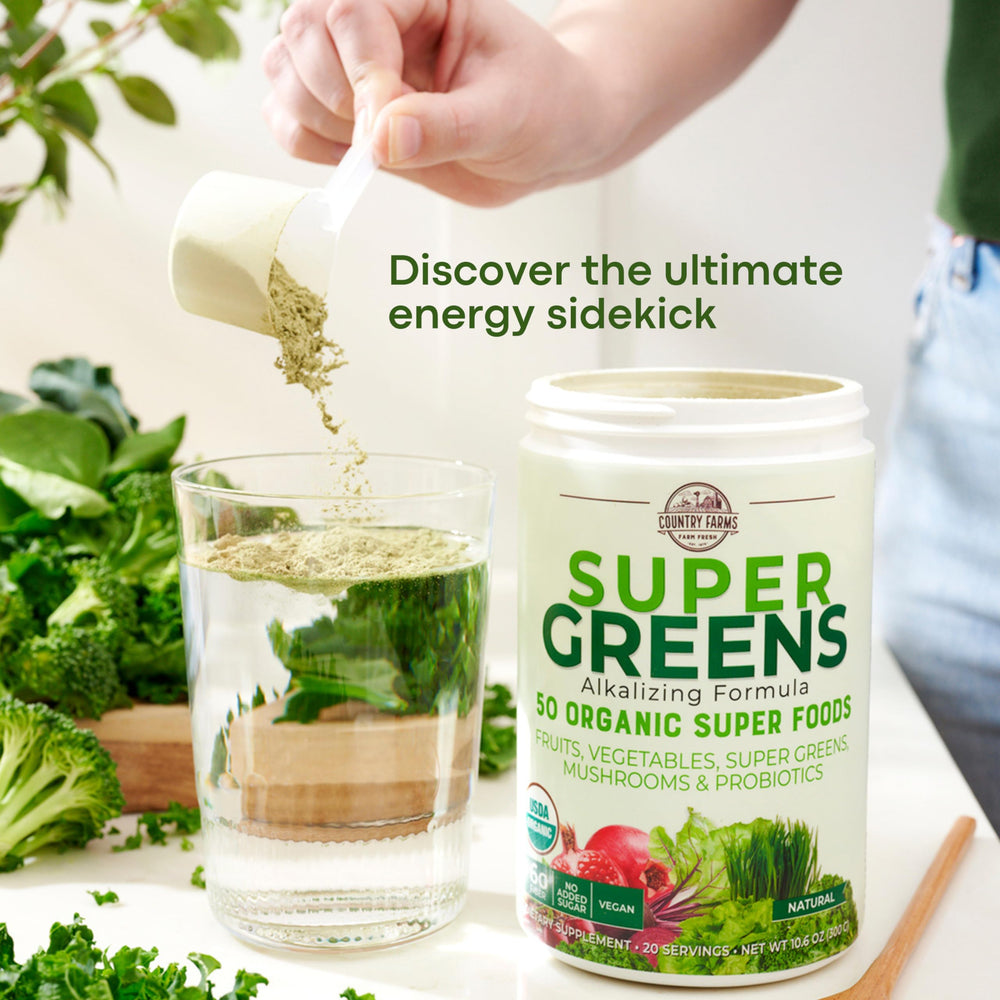 Glass of water beside Country Farms Super Greens package for easy mixing.
