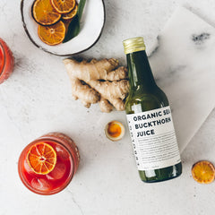 Erbology sea buckthorn juice close-up bottle glow highlighting beta-carotene and vitamin C.