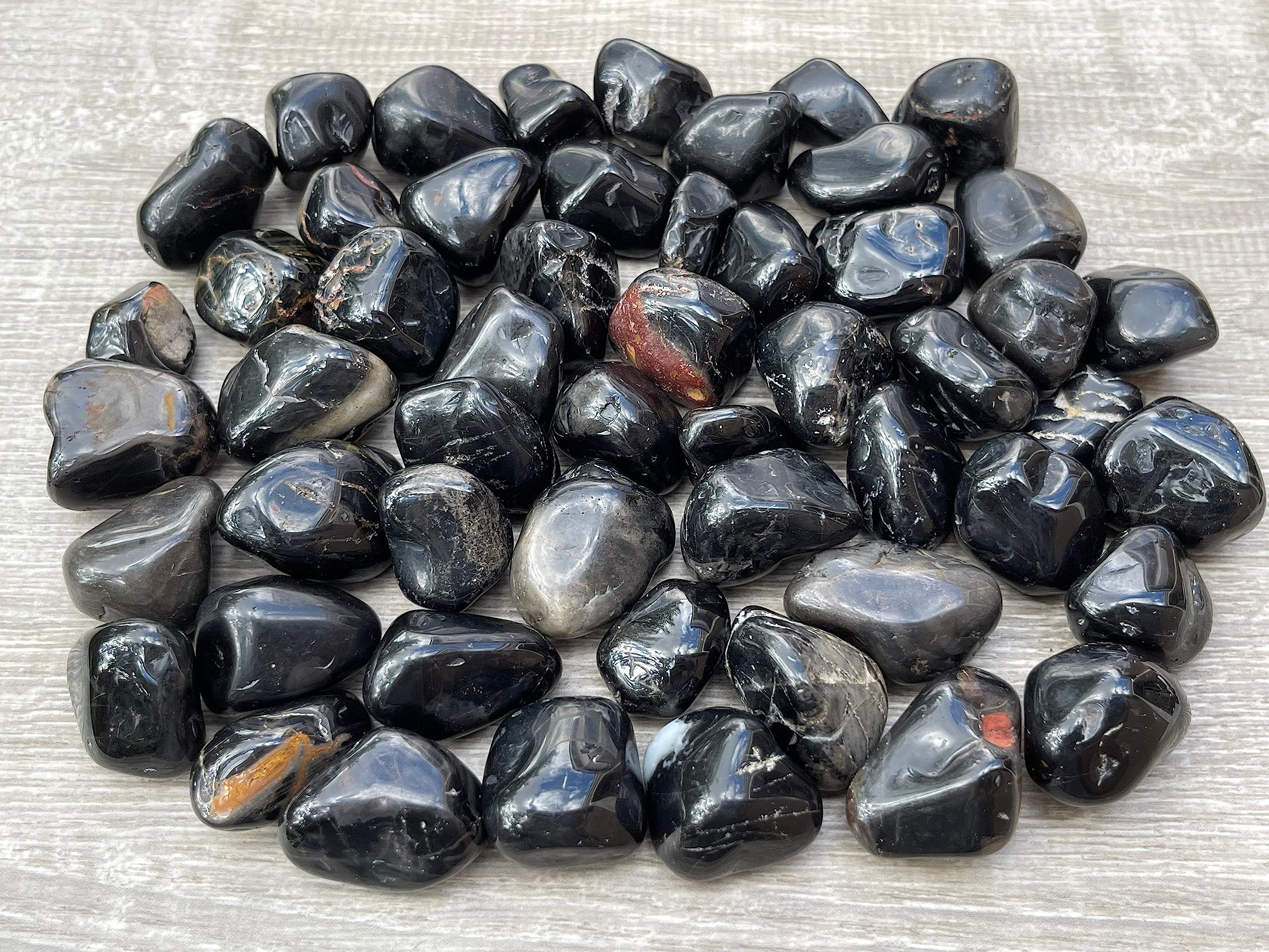 Close-up of GAF TREASURES Black Onyx tumbled stones showing a smooth polished surface