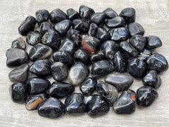Close-up of GAF TREASURES Black Onyx tumbled stones showing a smooth polished surface