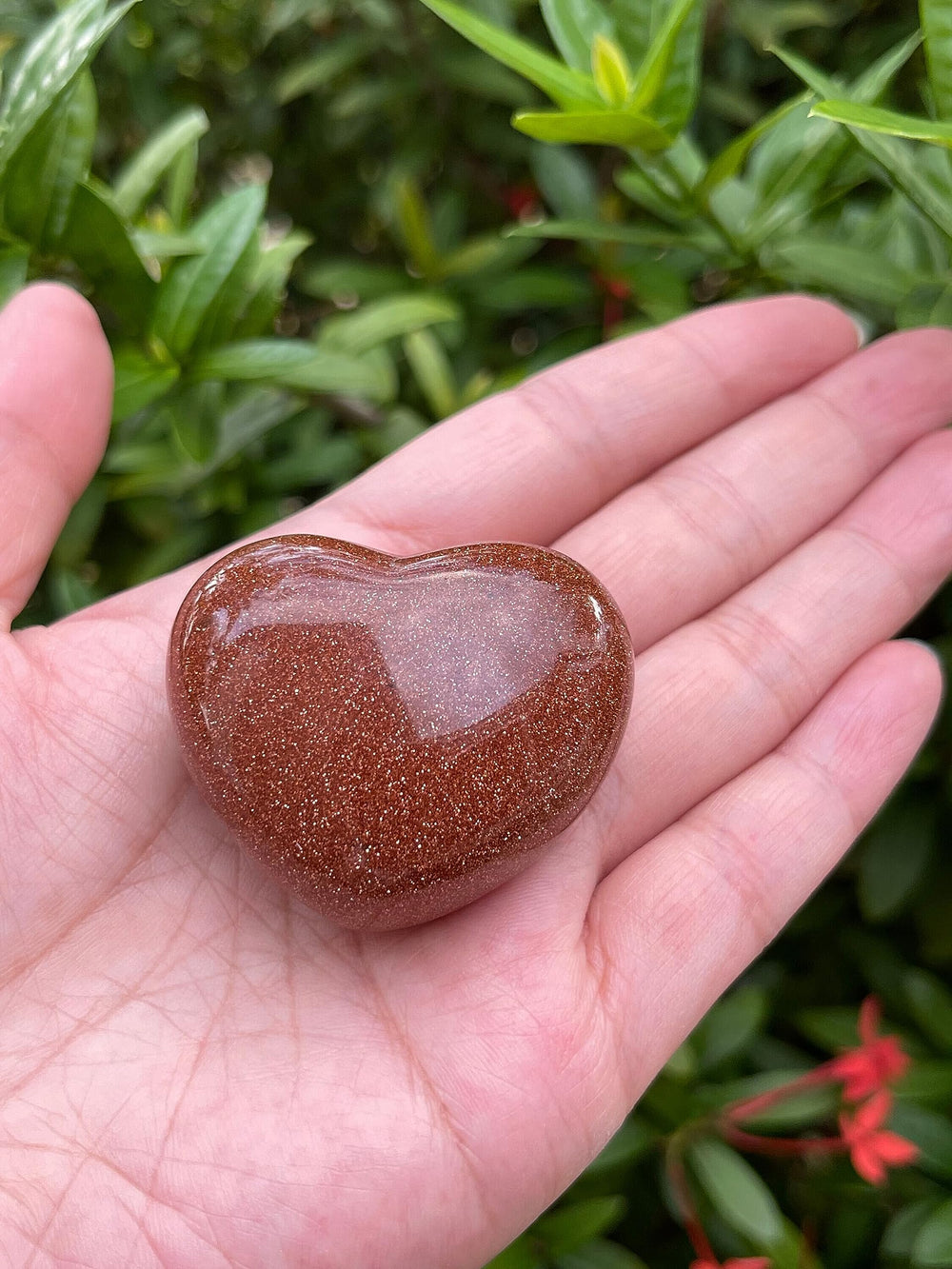 GAF Treasures Red Goldstone palm stone resting comfortably for grounding