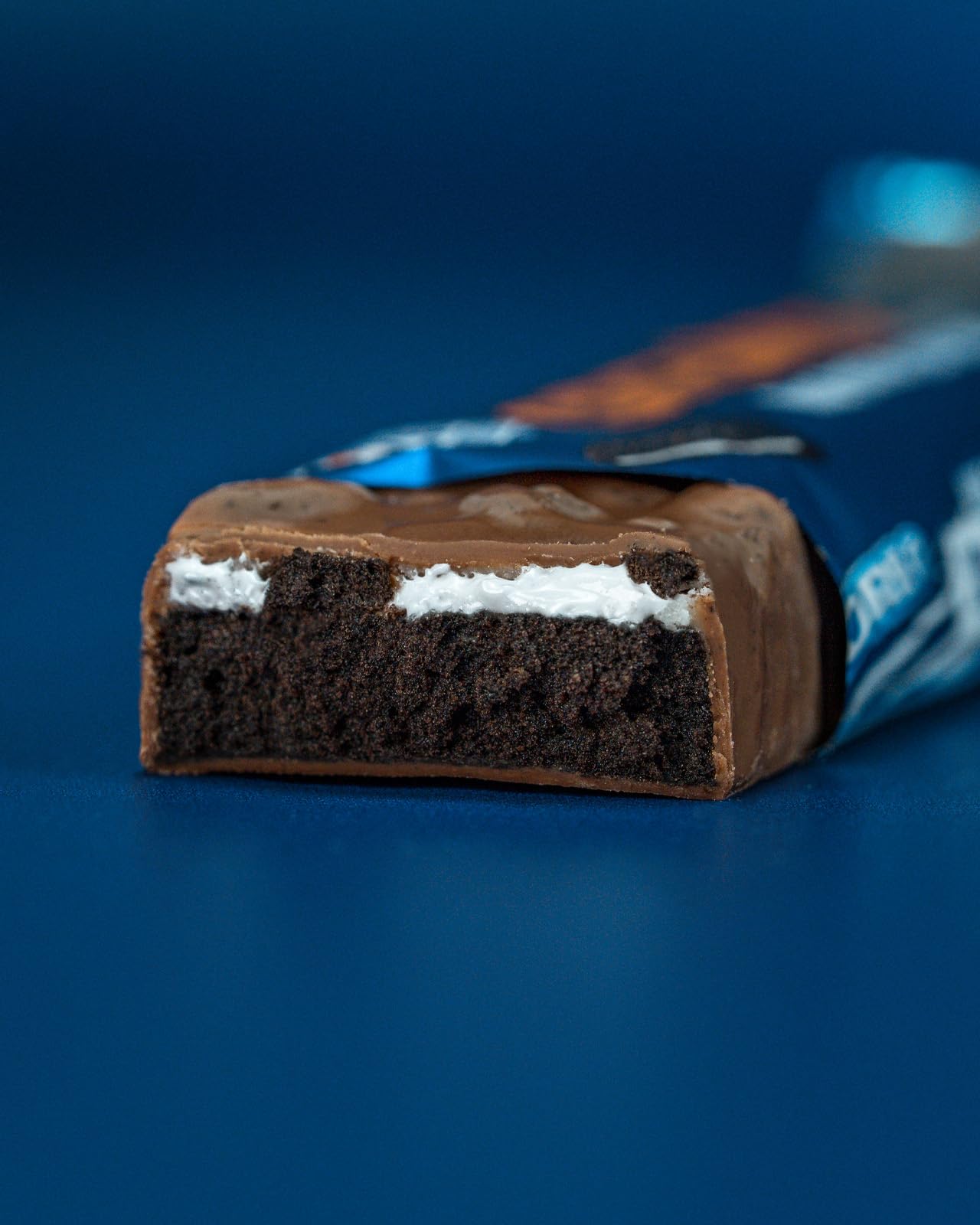 Grenade OREO High Protein Bar cross-section showing vanilla creme and Oreo cocoa layers.