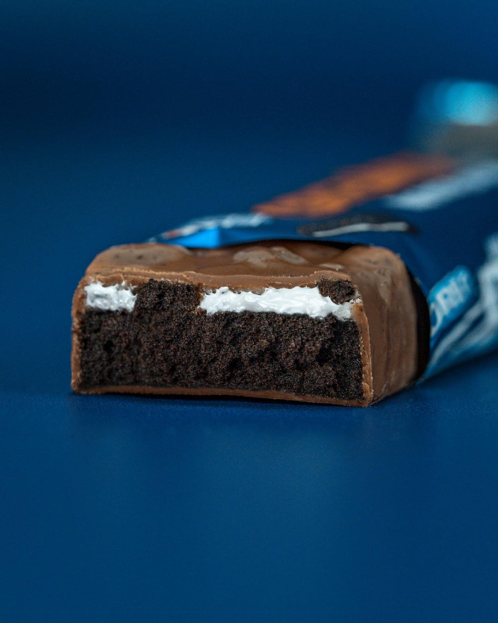 Grenade OREO High Protein Bar cross-section showing vanilla creme and Oreo cocoa layers.