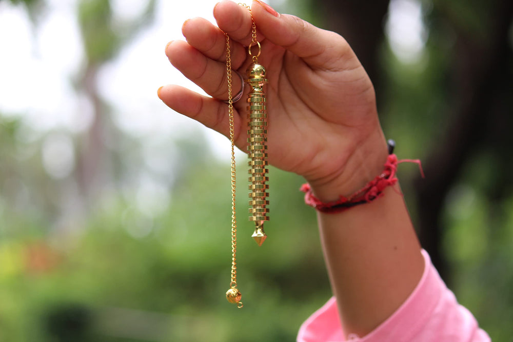 Jet International ISIS brass pendulum used in dowsing practice and spiritual routines.