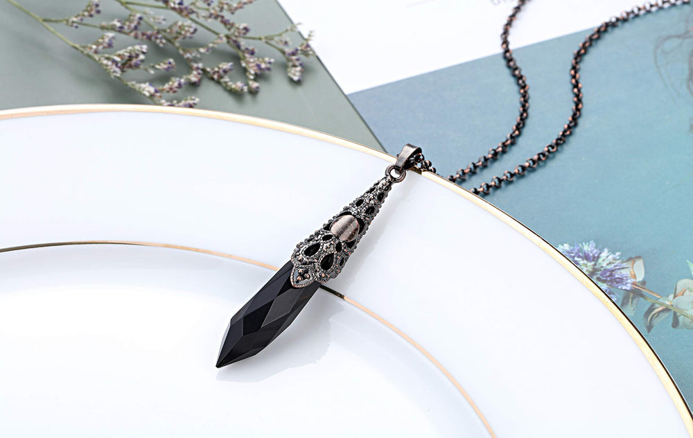 Close-up of Jovivi obsidian pendulum showing bronze cap for energy balancing rituals.