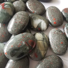 Loveliome bloodstone oval worry stone beside a fountain used as tranquil decor
