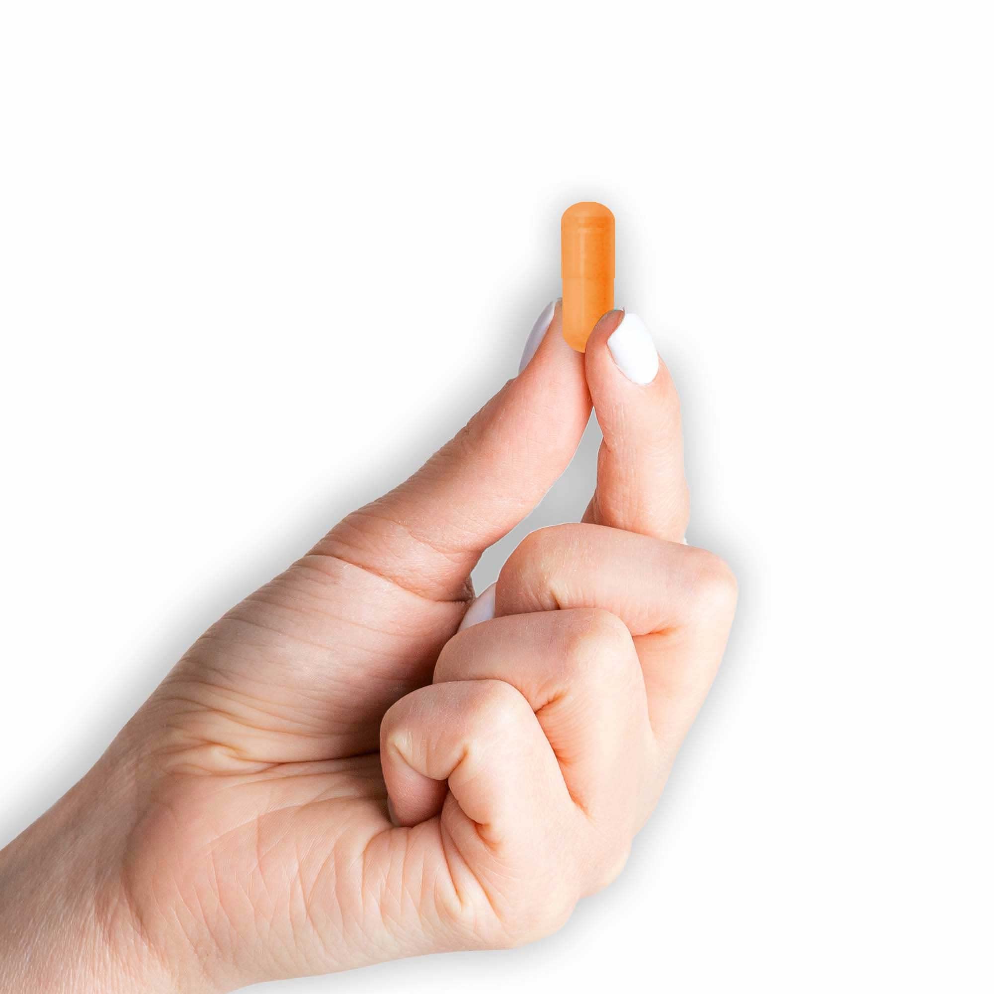 Capsules beside fresh turmeric root illustrating natural origins.