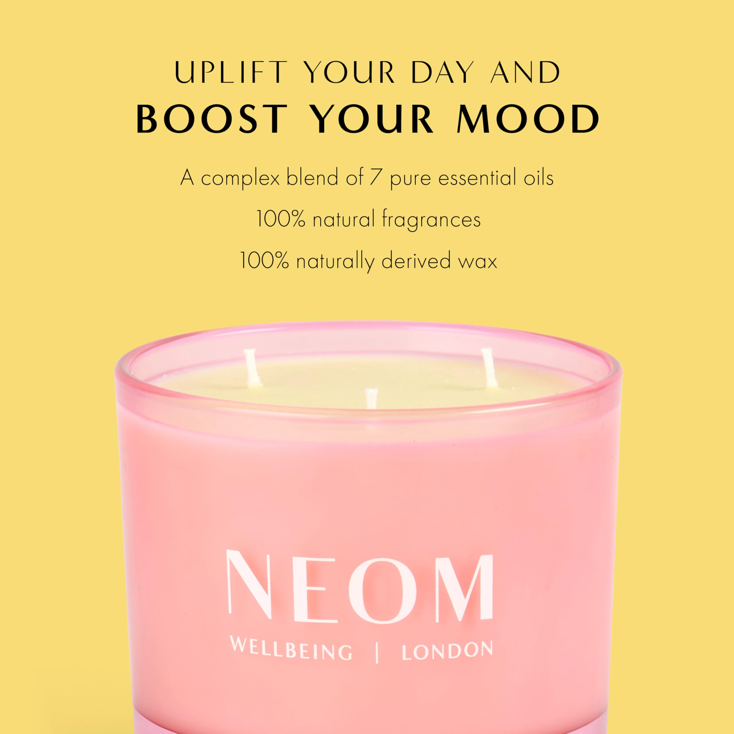 NEOM Great Day candle on table with soft glow.