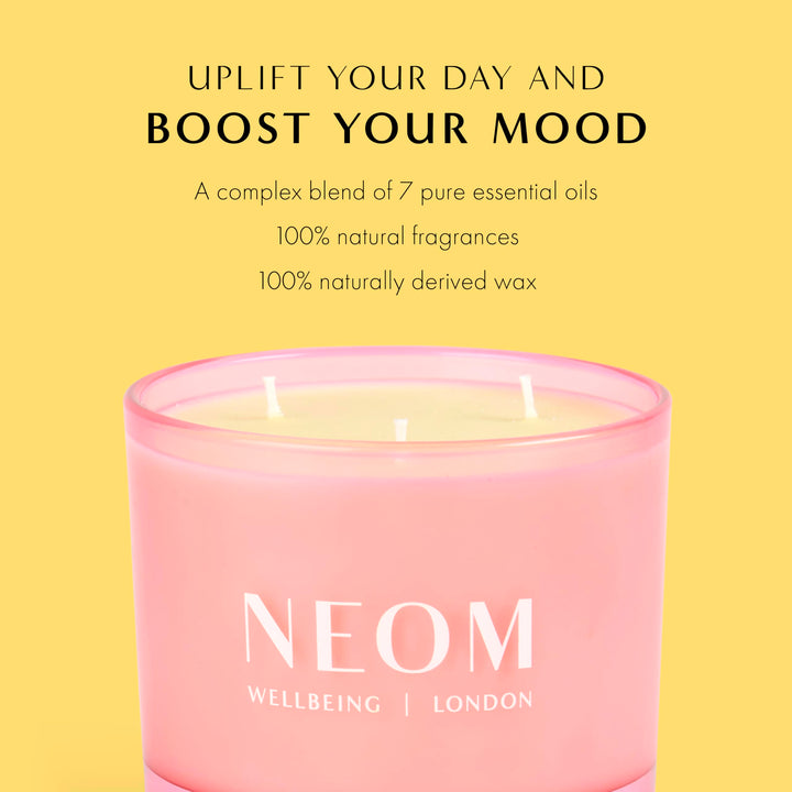 NEOM Great Day candle on table with soft glow.
