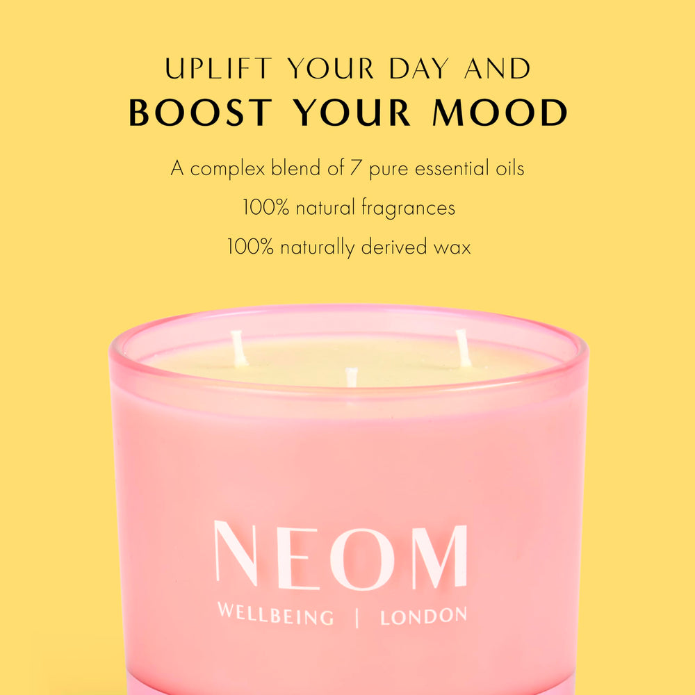 NEOM Great Day candle on table with soft glow.