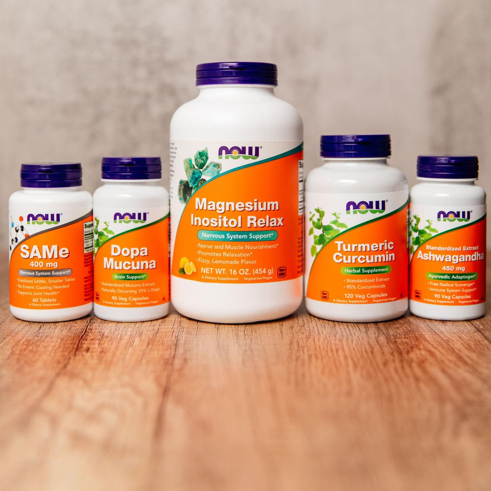 NOW Foods Turmeric Curcumin capsules in a glass with water.