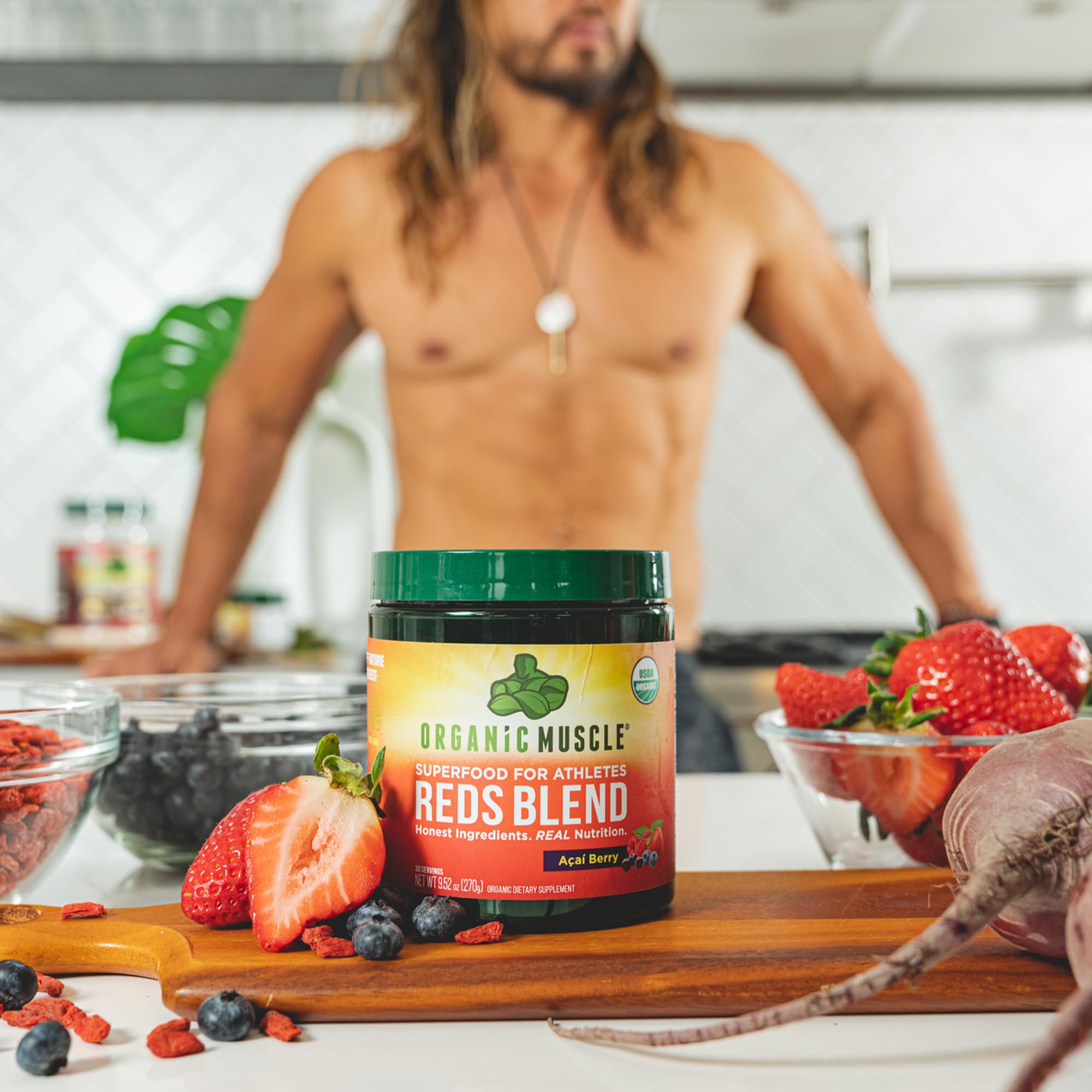 Organic Muscle Reds Powder packaging next to fresh berries.