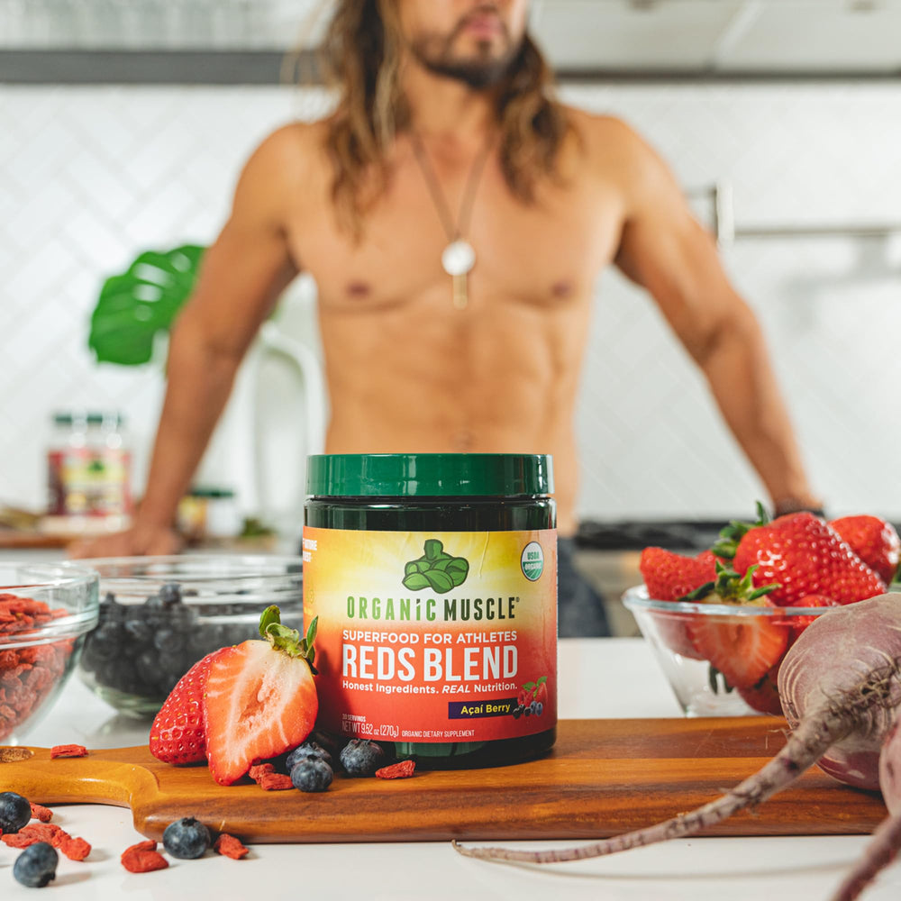 Organic Muscle Reds Powder packaging next to fresh berries.