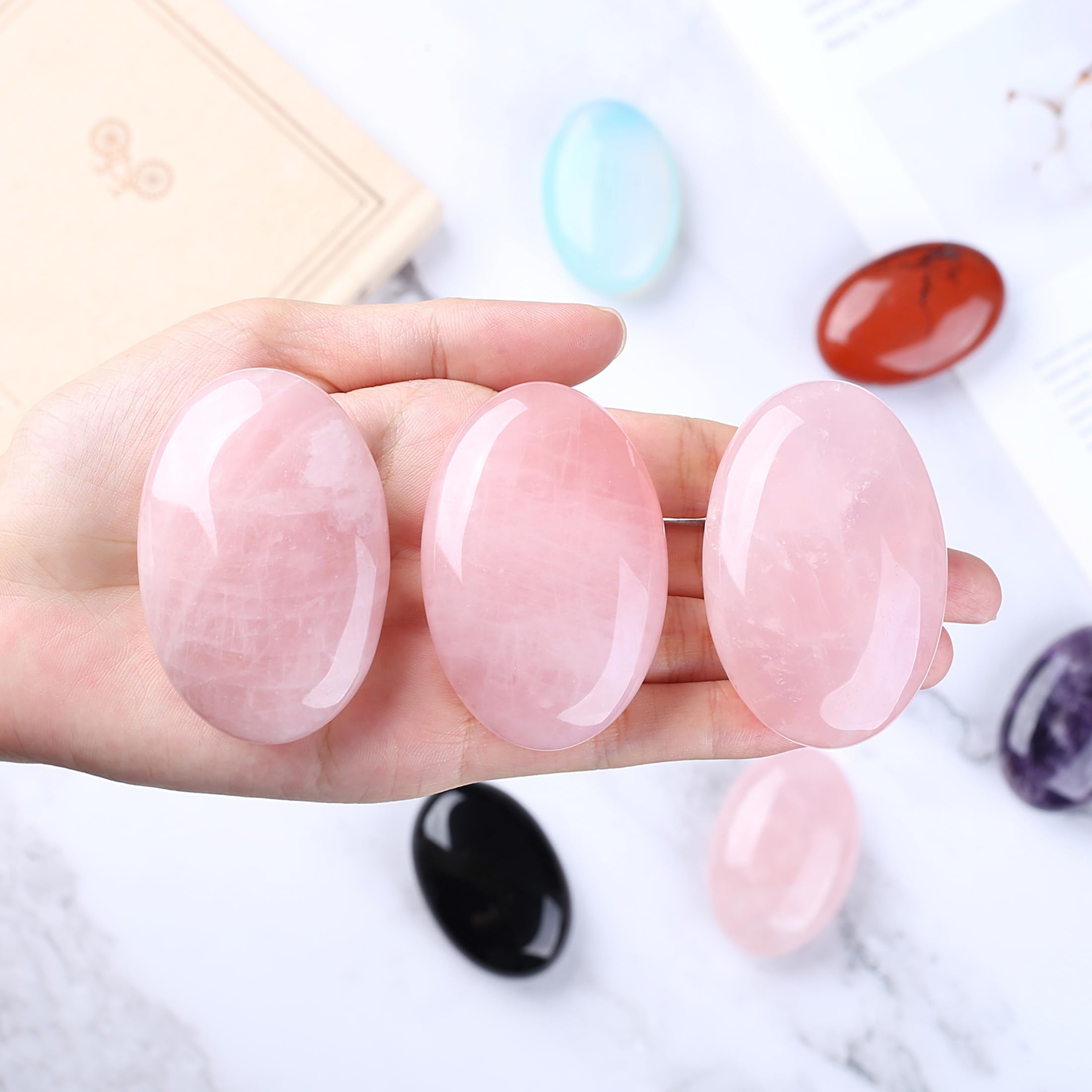 Closeup of QINJIEJIE rose quartz palm stone showing smooth polish and pink hue.