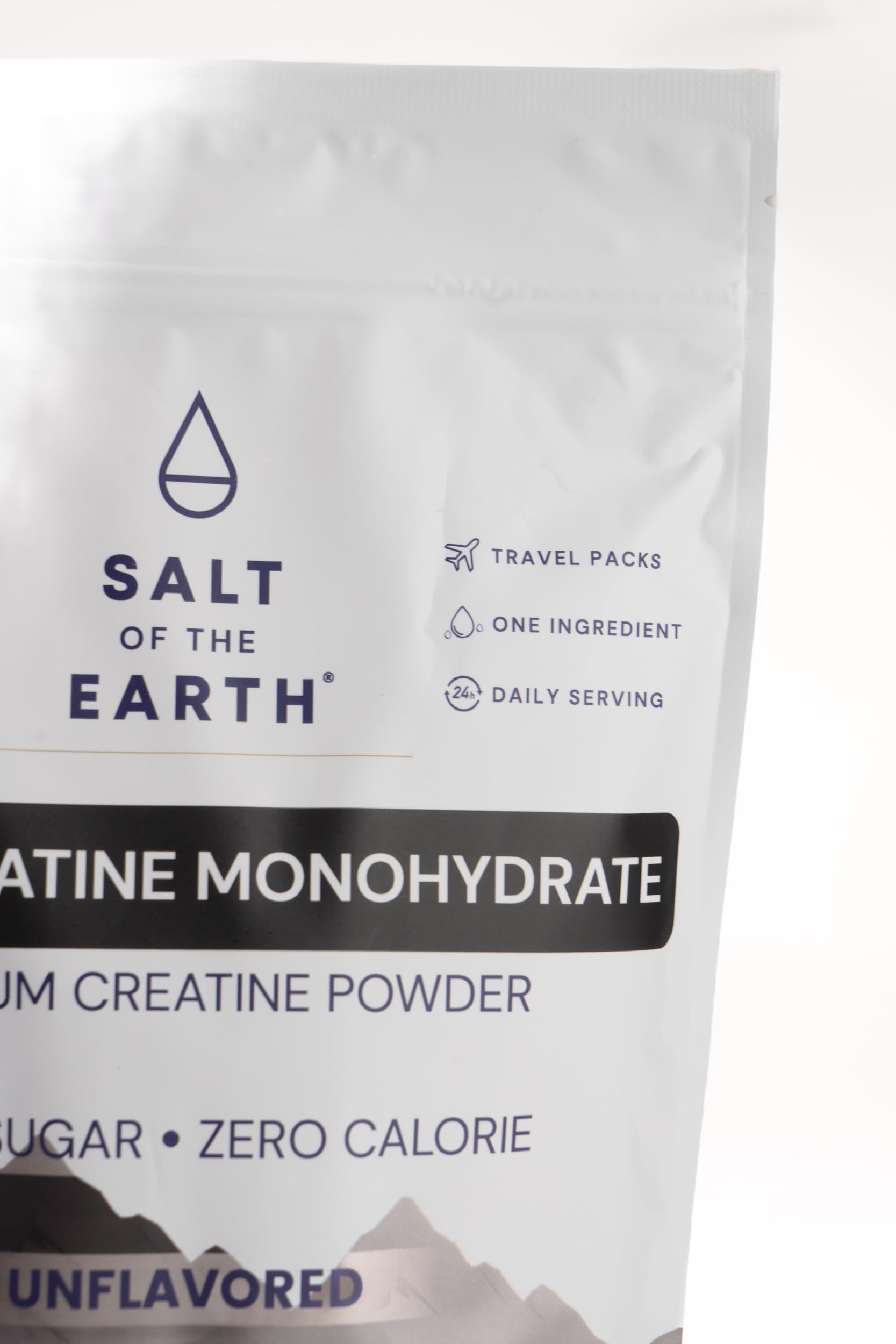 Salt of the Earth Creatine tub beside a glass of water.