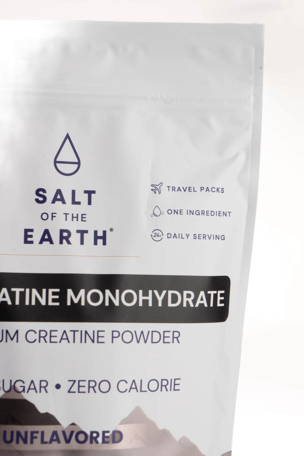 Salt of the Earth Creatine tub beside a glass of water.