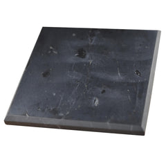 Shungite World polished 100x100mm tile shown as a balanced charging plate on a desk