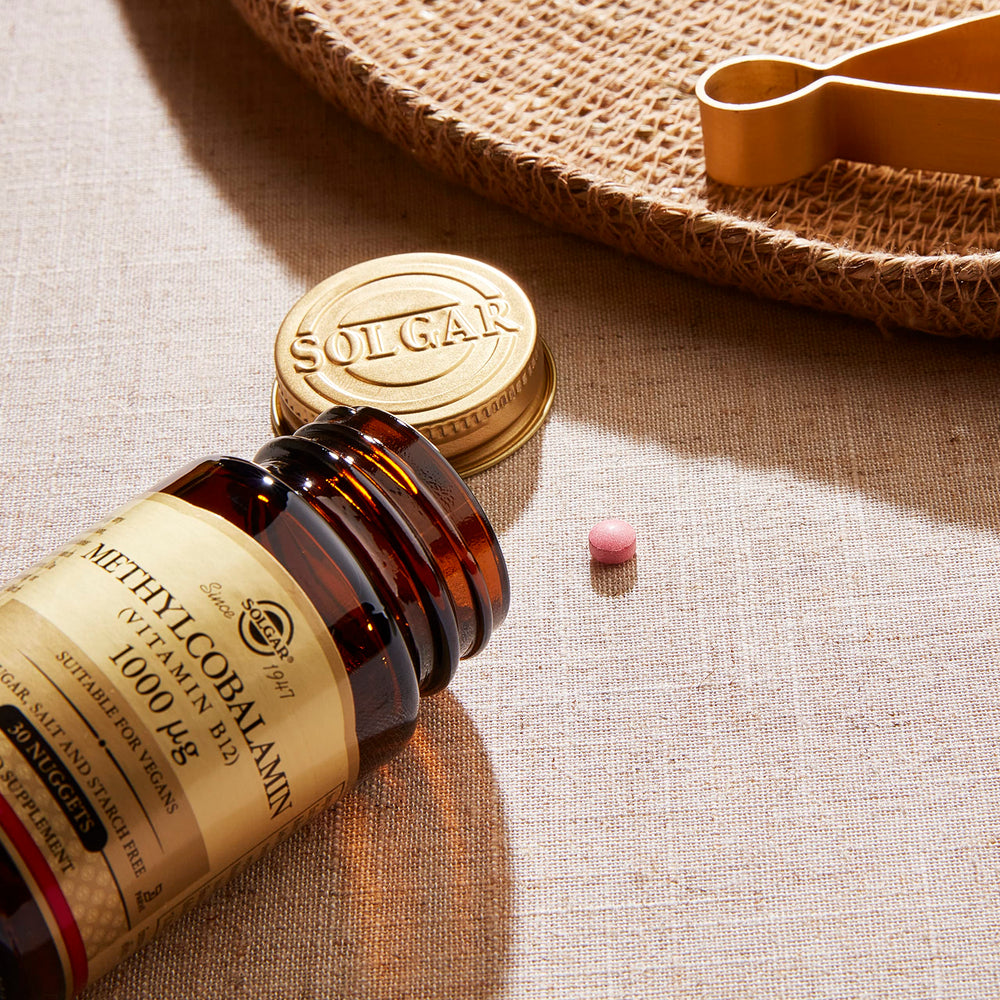 Solgar Methylcobalamin 1000 mcg Nuggets on table with glass of water for easy swallowing.
