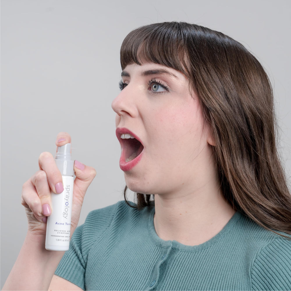 Sprayology Acne Tonic bottle beside a glass of water for easy daily use.