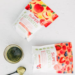 SPRIGS peach-flavored greens powder in a glass for daily nutrition