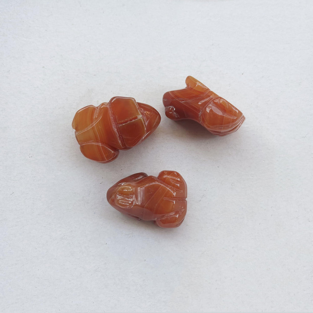 Sunshcat hand carved frog gemstone emphasizing unique grain and petite size.