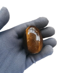 Sunshcat tiger's eye egg on wooden stand decorating a desk.